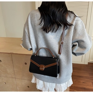Détail de la bandoulière réglable et de la poignée sur un sac carré bicolore chic