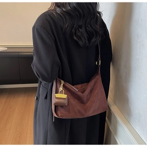 Detail view of deep brown suede tote bag with golden chain charm accessory