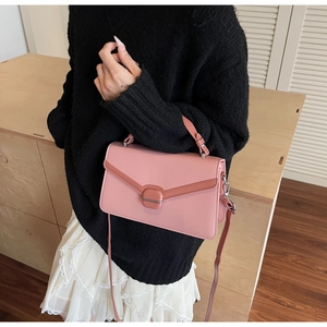 Détail d'un sac bandoulière rose avec serrure métallique porté sur un pull noir