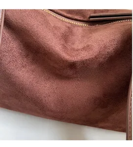 Close-up of brown faux suede fabric texture and stitching detail on the shoulder bag