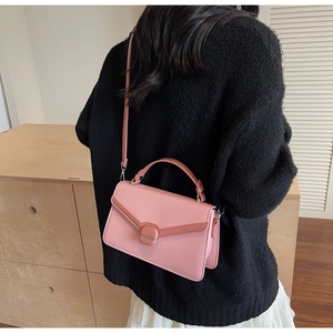 Modèle portant un sac bandoulière rose avec bord contrasté et fermoir métallique