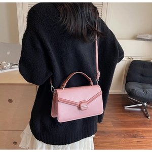 Sac bandoulière en cuir mat rose avec fermoir en métal porté par un mannequin femme