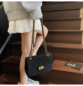 Détail du sac matelassé en velours noir avec bandoulière chaîne et boule dorée