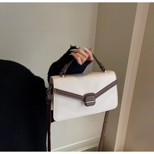 Détail d'un sac à bandoulière crème avec bordure marron et fermoir métallique carré