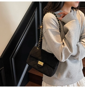 Détail de la texture en velours matelassé et du fermoir doré sur ce sac noir chic
