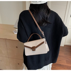 Detail of a chic contrast handbag with cream leather and brown accents in a lifestyle setting