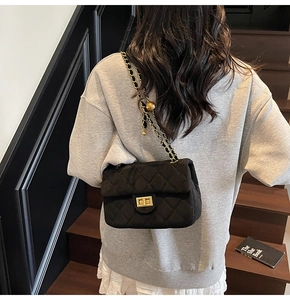 Détail du sac bandoulière matelassé en velours noir avec chaîne et boucle dorée