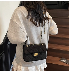 Gros plan d'un sac bandoulière en velours noir avec chaîne dorée et matelassage
