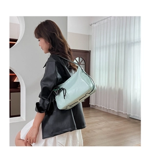 Dettaglio borsa tote verde menta in pelle lucida con ciondolo a pois sulla modella