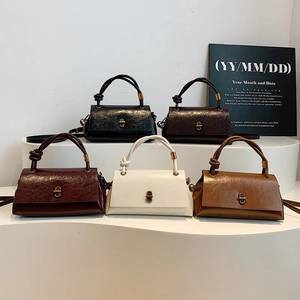 Minimalist glossy leather crossbody bag with knot handle and vintage gold lock hardware