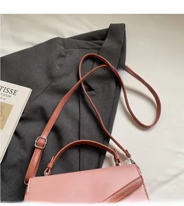 Detail of pink and brown color-block handbag with adjustable strap and top handle
