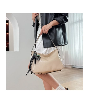 Dettaglio di una borsa tote in pelle verniciata beige con cuore nero e borchie dorate