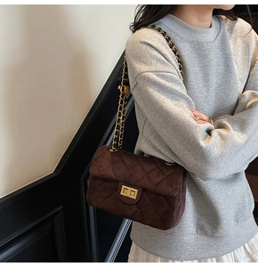 Détail du sac bandoulière en velours matelassé marron foncé avec chaîne dorée et fermoir