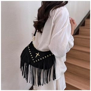 Detail of black suede hobo bag with long tassels, gold studs and cross hardware