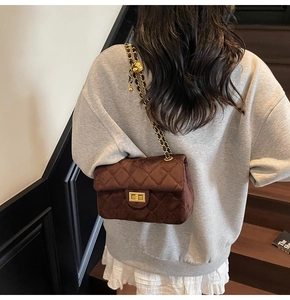 Détail d'un sac bandoulière en velours marron avec chaîne dorée et bille de réglage