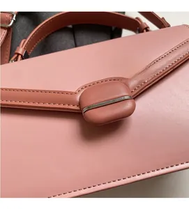 Close-up of salmon pink leather handbag with premium metal buckle and stitching details