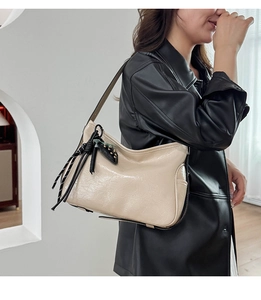 Dettaglio borsa tote color crema lucida con nappa intrecciata e tracolla nera