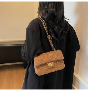 Sac à bandoulière en velours matelassé marron avec chaîne dorée sur un blazer noir