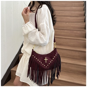 Detail of burgundy suede crescent bag with metal rivets and long fringe tassels