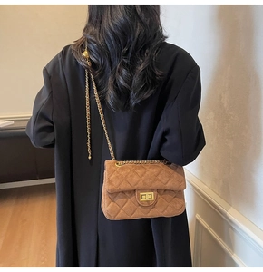 Détail du sac bandoulière en velours matelassé marron avec chaîne dorée et boucle à bille