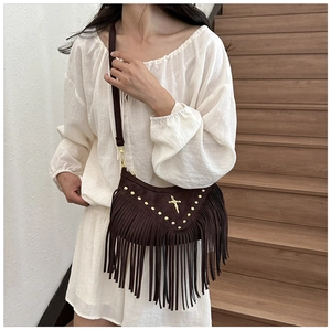 Detail of dark brown faux suede crossbody bag with long tassels and gold metal studs