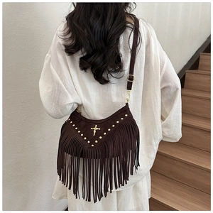 Detail of dark brown suede bag with gold rivets, cross motif and long decorative tassels