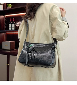 Dettaglio borsa tote in pelle nera lucida con ciondolo a cuore in ambiente retrò
