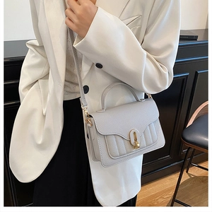 Close-up of light grey litchi grain leather bag with a gold oval metal buckle and stitching