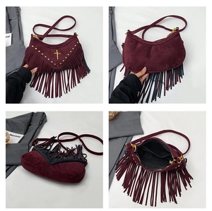 Detail view of burgundy suede crossbody bag with metal rivets and long fringe