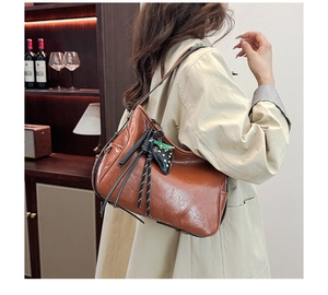 Dettaglio della borsa tote vintage in pelle marrone con ciondolo a fragola e corde