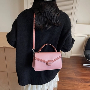 Sac à main rose avec surpiqûres en V porté par un mannequin dans un intérieur