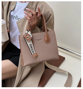 Detail of a brown woven texture tote bag with leather handles and fashion scarf