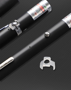 Macro detail of matte black laser pointer with safety warning label and metal clip