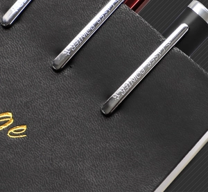 Macro detail of rechargeable metal laser pointers clipped to black leather folder