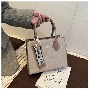 Close-up of beige fabric tote bag with brown leather trim and decorative printed silk scarf