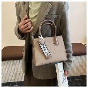 Detail of structured khaki tote bag with top handles and adjustable shoulder strap