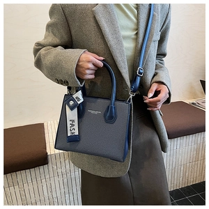 Detail view of woven leather tote bag with elegant dark blue handles and shoulder strap
