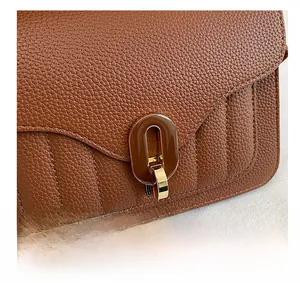 Detail of U-shaped buckle in brown acrylic and gold on lychee leather handbag