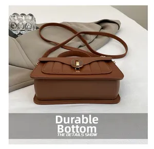 Detail showing durable bottom studs and lychee pattern leather of the brown handbag