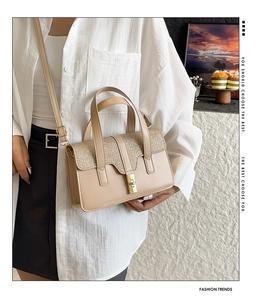 Close-up of beige leather shoulder bag with sequin panel and golden metal lock