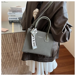 Close-up of grey-green textured tote bag with FASHION & BAGS print and decorative strap