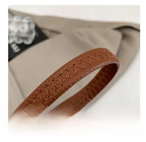 Detail of brown litchi leather strap with handcrafted W-shaped stitching on the handbag