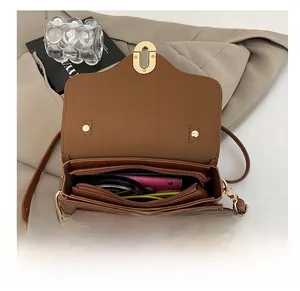 Internal view of brown crossbody bag showing multi-layer compartments and gold lock