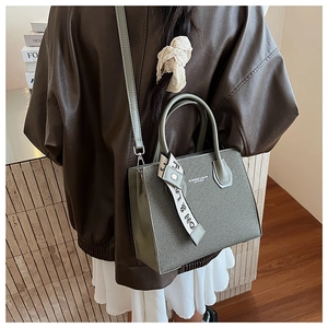 Olive green structured handbag with decorative scarf and shoulder strap on model