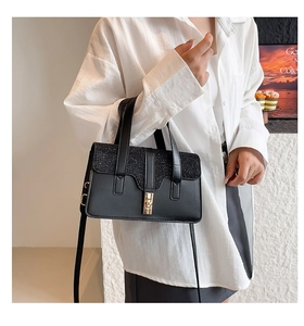 Detail of black crossbody bag featuring a shimmering glitter flap and gold metal lock