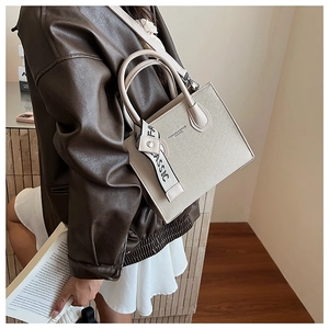 Detail of beige contrast color handbag featuring a stylish classic printed ribbon strap