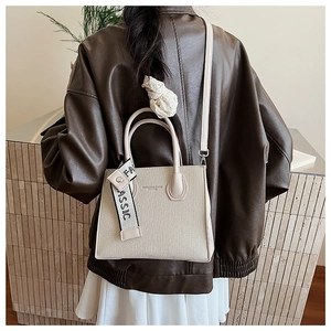 Beige luxury crossbody bag shown on model with contrast strap and fashion embossing