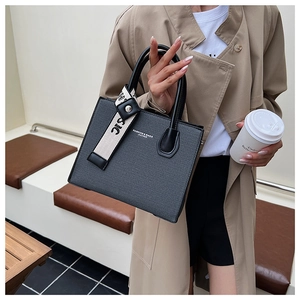 Detail of black faux leather tote bag featuring contrast straps and fashion lettering