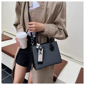 Detail of dark grey textured leather tote bag with a striped classic charm and shoulder strap