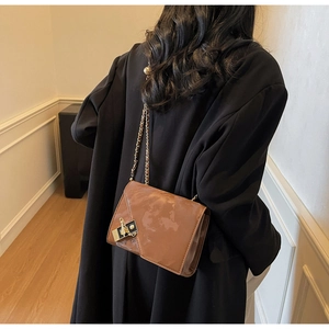Close-up of brown marble texture crossbody bag with gold chain strap on black blazer